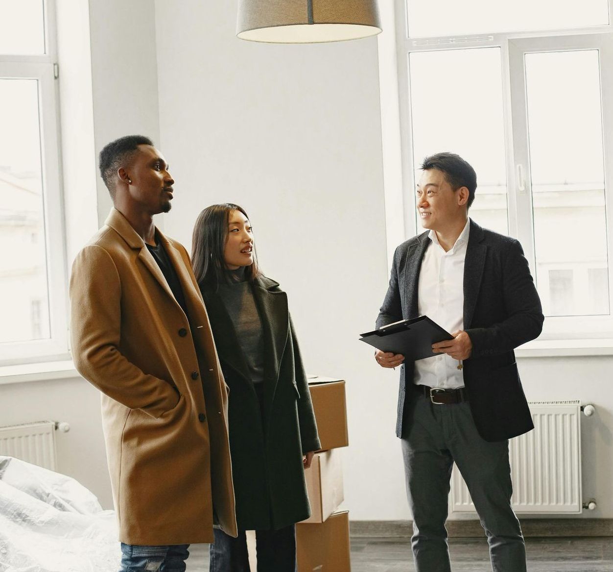 Three people are standing in a room talking to each other.