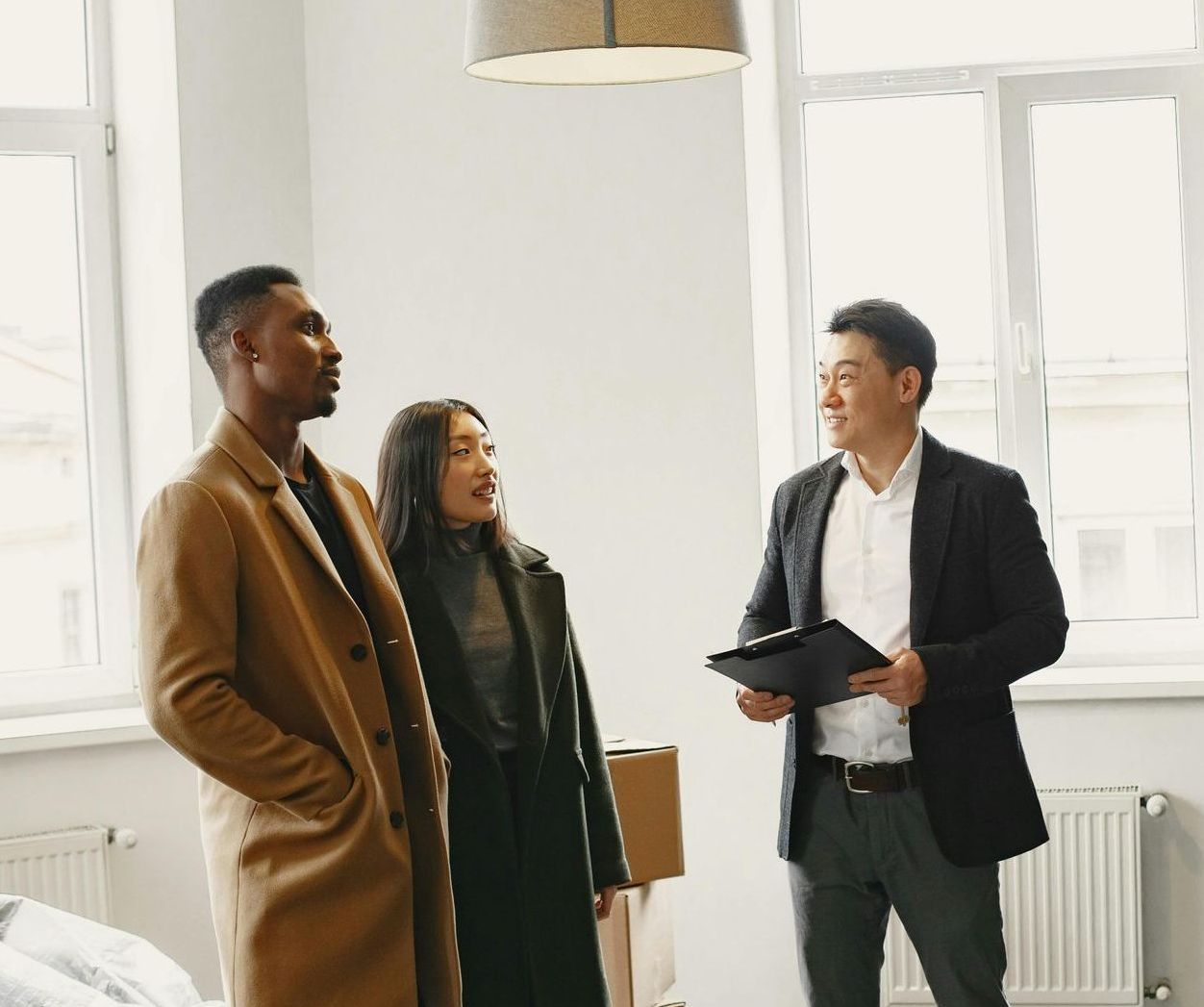 A man and a woman are standing in a room with a man holding a clipboard.