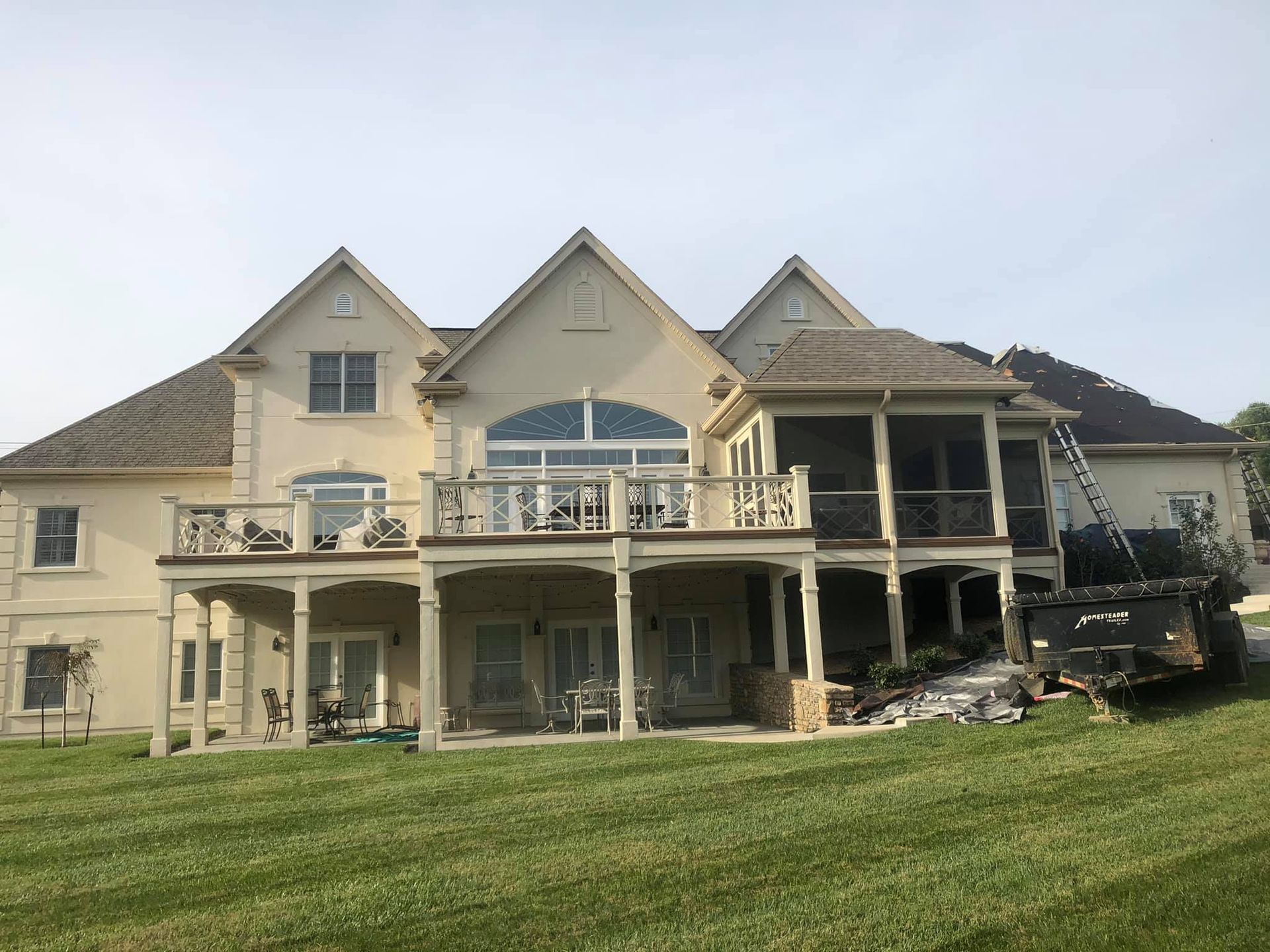 A large house with a lot of windows and balconies is sitting on top of a lush green field.