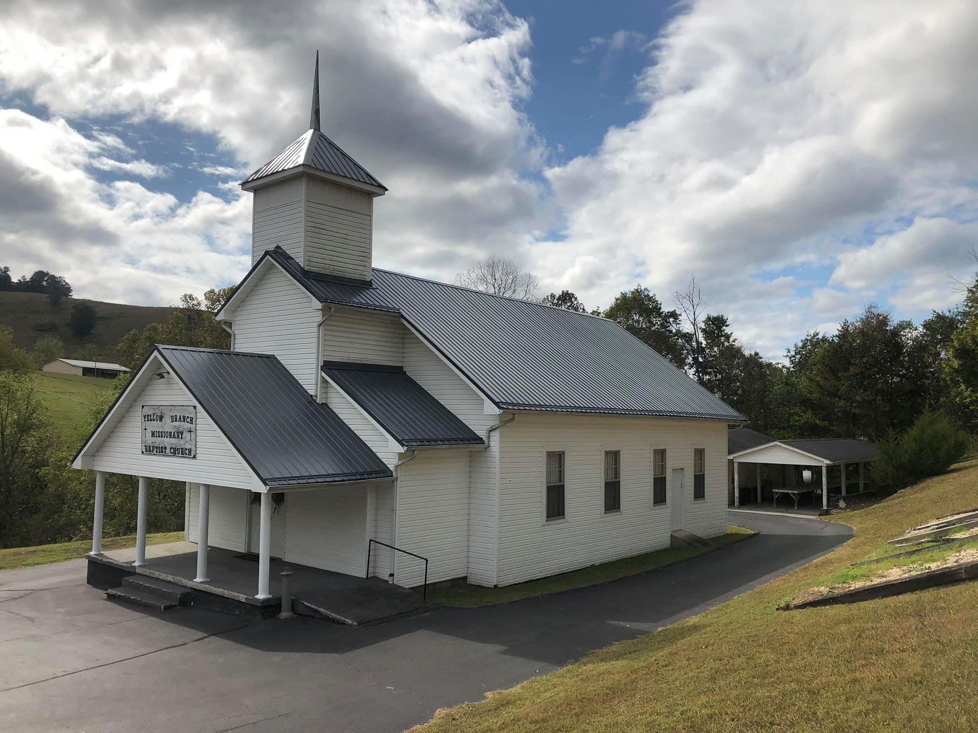 A car is parked in front of a large brick house.