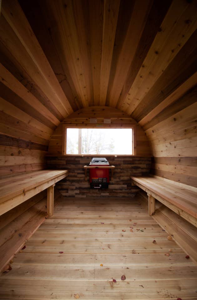 The inside of a wooden barrel with benches and a window.