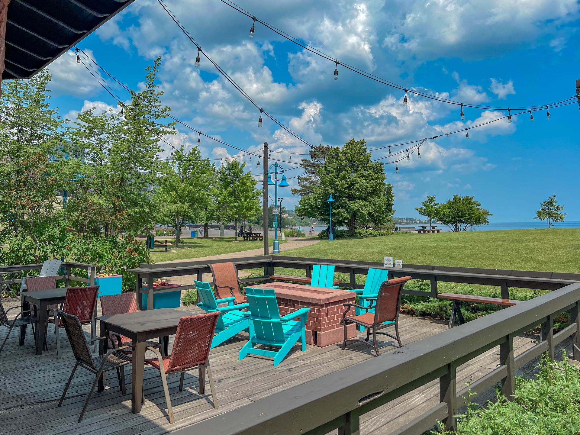 A deck with tables and chairs and a fire pit.