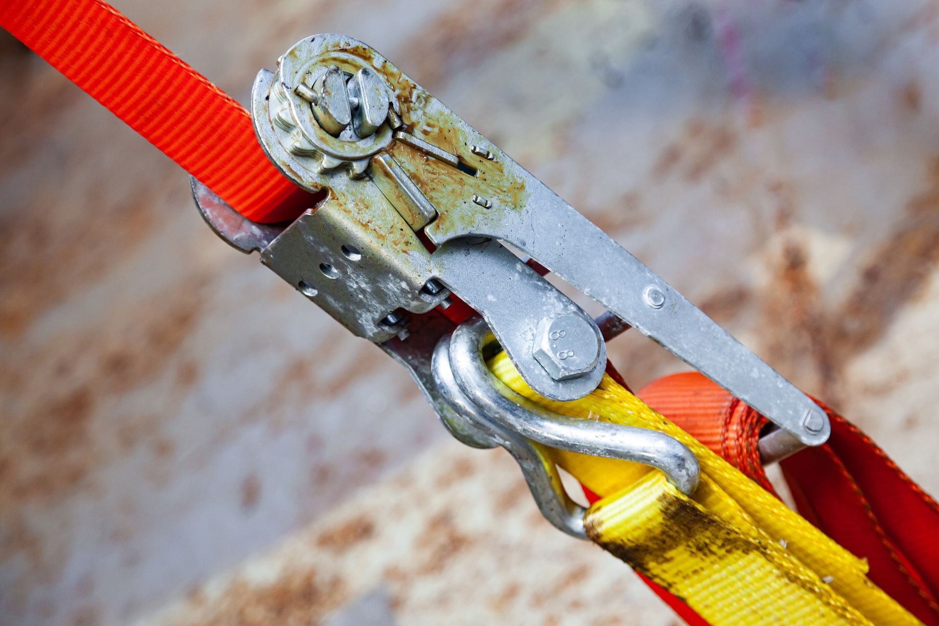 Tight orange cargo strap with ratchet lock, shown diagonally in close-up Tight orange cargo strap with ratchet lock, shown diagonally in close-up