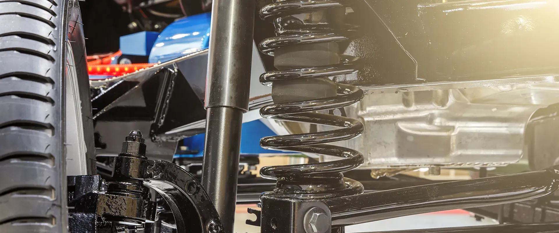 Close-up of a vehicle's suspension system, showing a coil spring, shock absorber, and other mechanical parts.