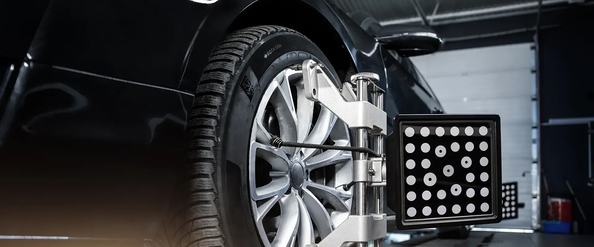 Car tire being aligned on a machine in a garage.