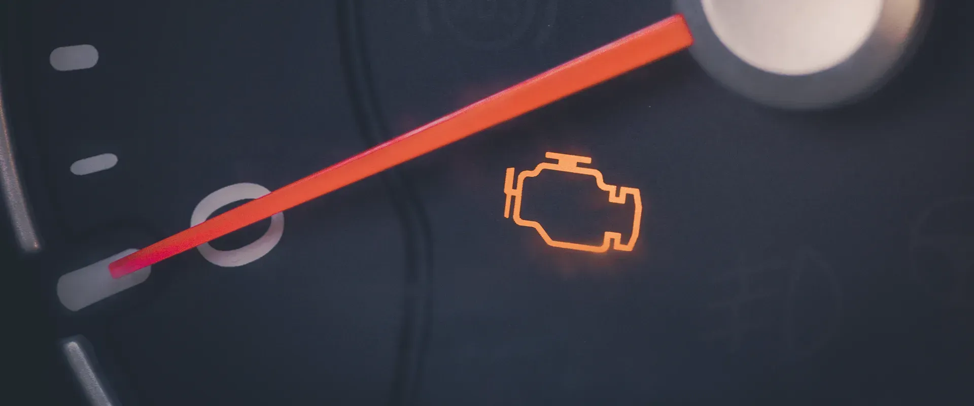 Dashboard displaying the check engine light. An orange needle points slightly to the right.