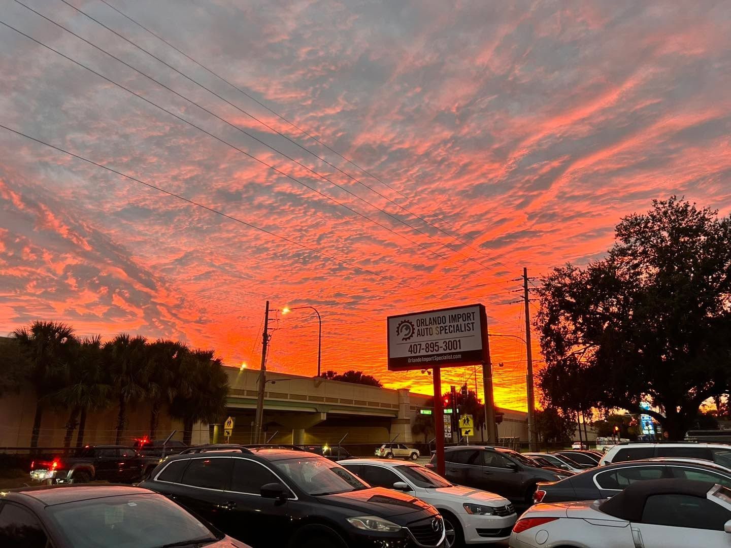 Sunset over a car lot with a fiery red and orange sky.