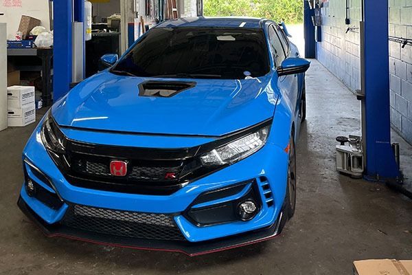 Blue Honda Civic Type R in an auto repair shop.