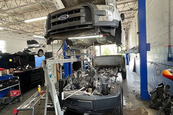Ford van raised in a garage, engine removed, possibly under repair.