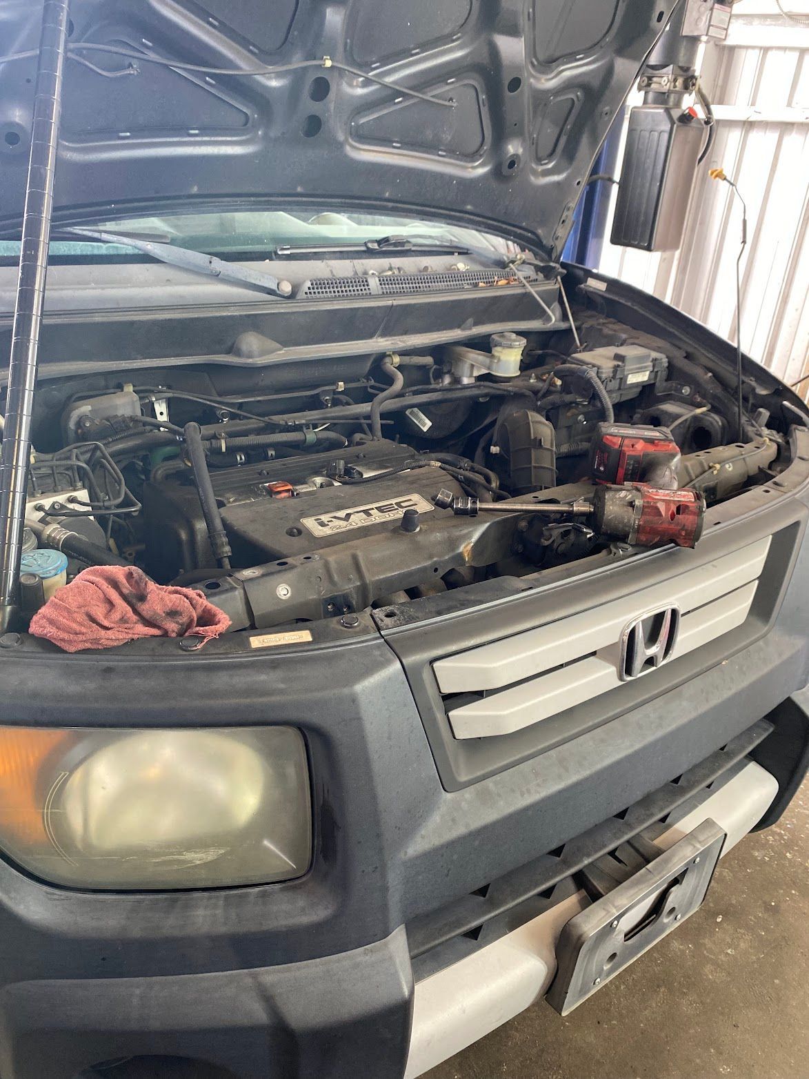 Honda Element with hood open, showing engine compartment at a garage.