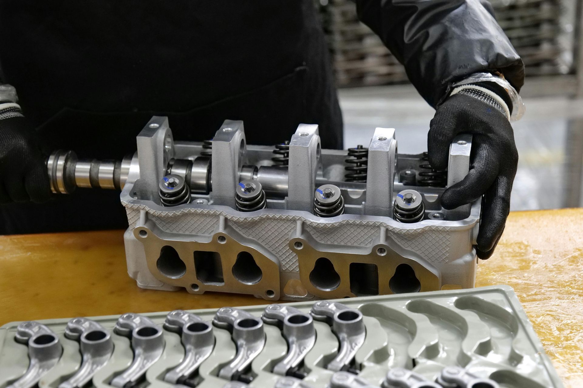 Person assembling engine cylinder head wearing gloves.