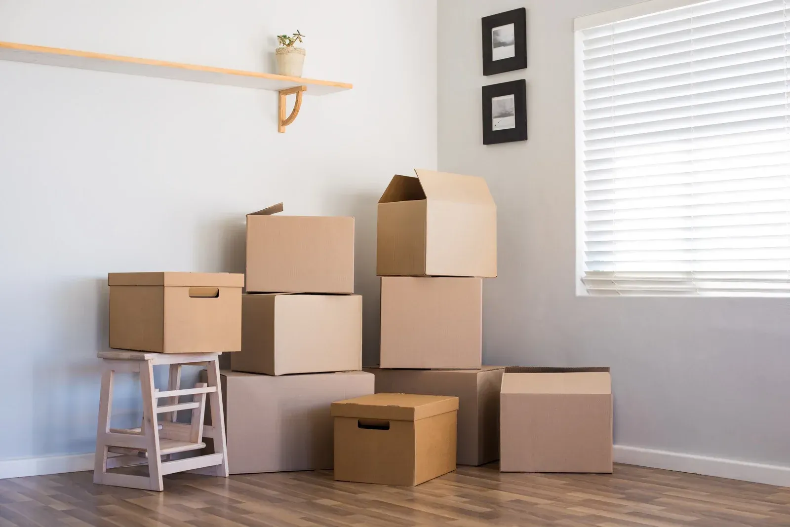 Cardboard boxes stacked in a room, ready for moving. Empty room with a window and a shelf.