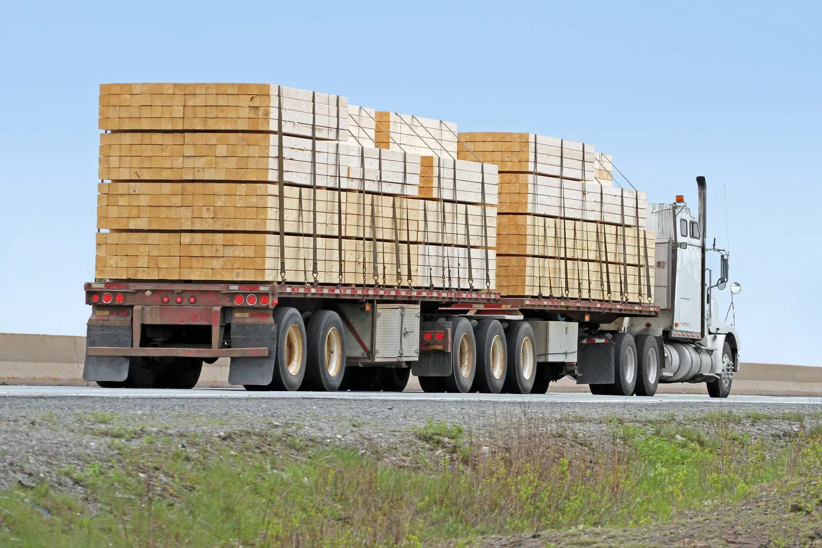 A semi truck is carrying a large load of wood.