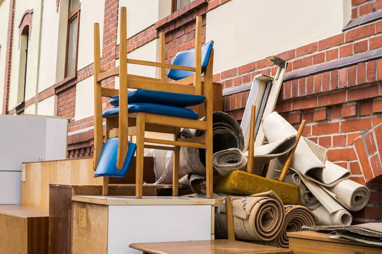 A pile of furniture is stacked on top of each other in front of a brick building.