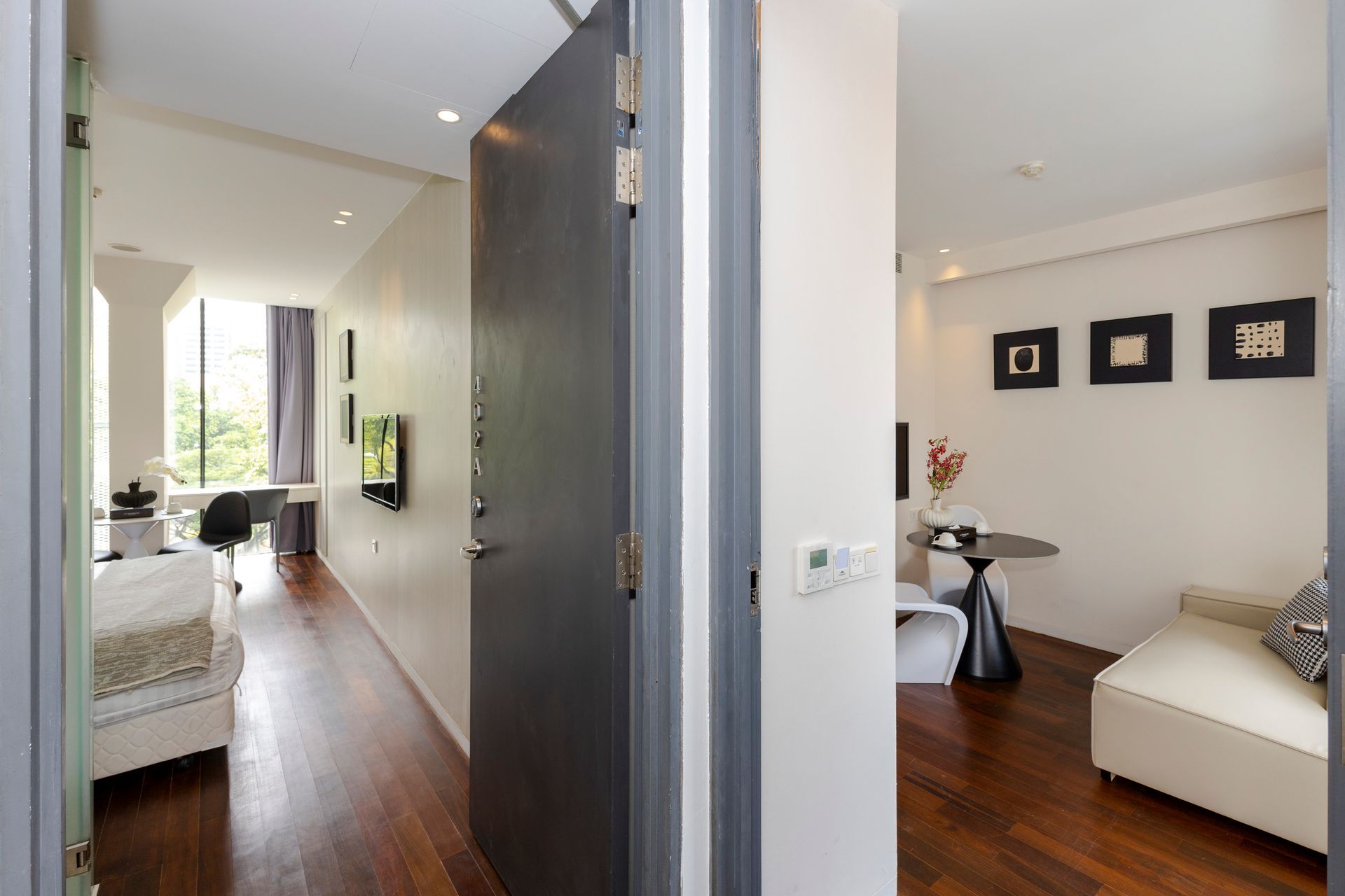 Open apartment doorway revealing a living area with furniture and a dining area with artwork.