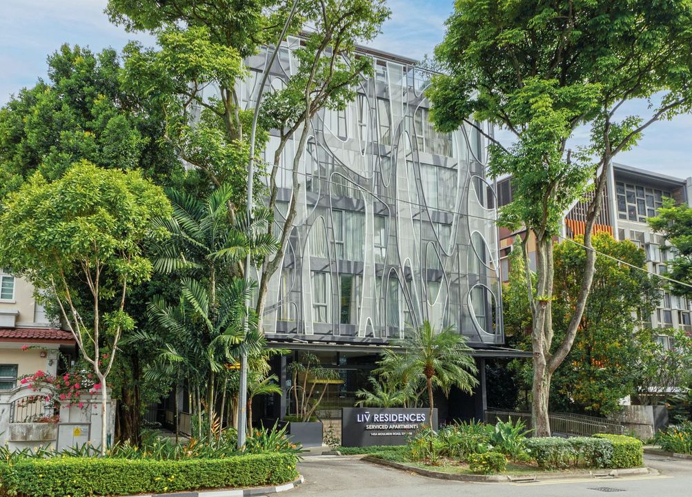Modern building facade with unique wooden latticework, surrounded by lush greenery.