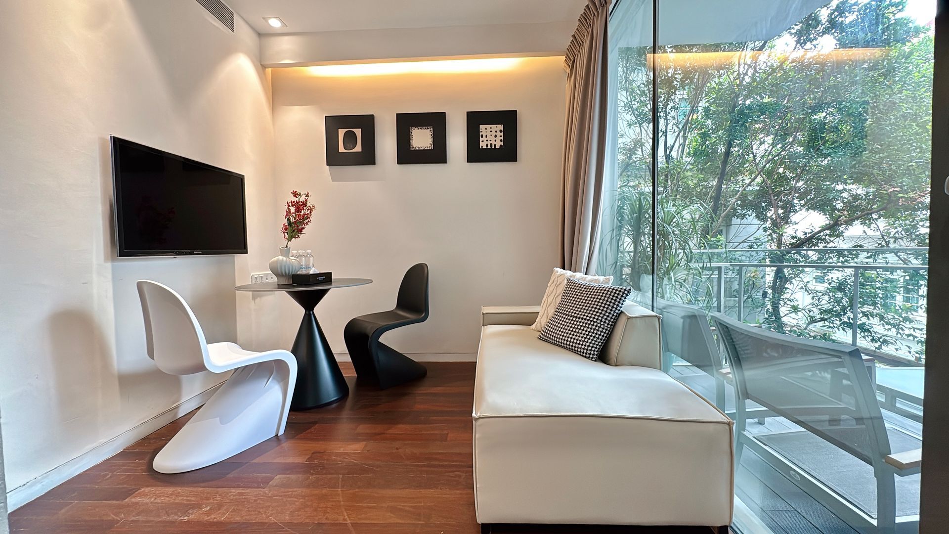 Small apartment living room with TV, modern furniture, and a balcony with a view.