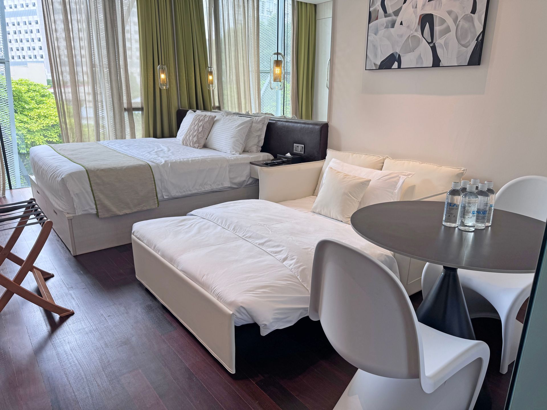 Cozy studio apartment with a bed, sofa bed, small table, and chairs; natural light.