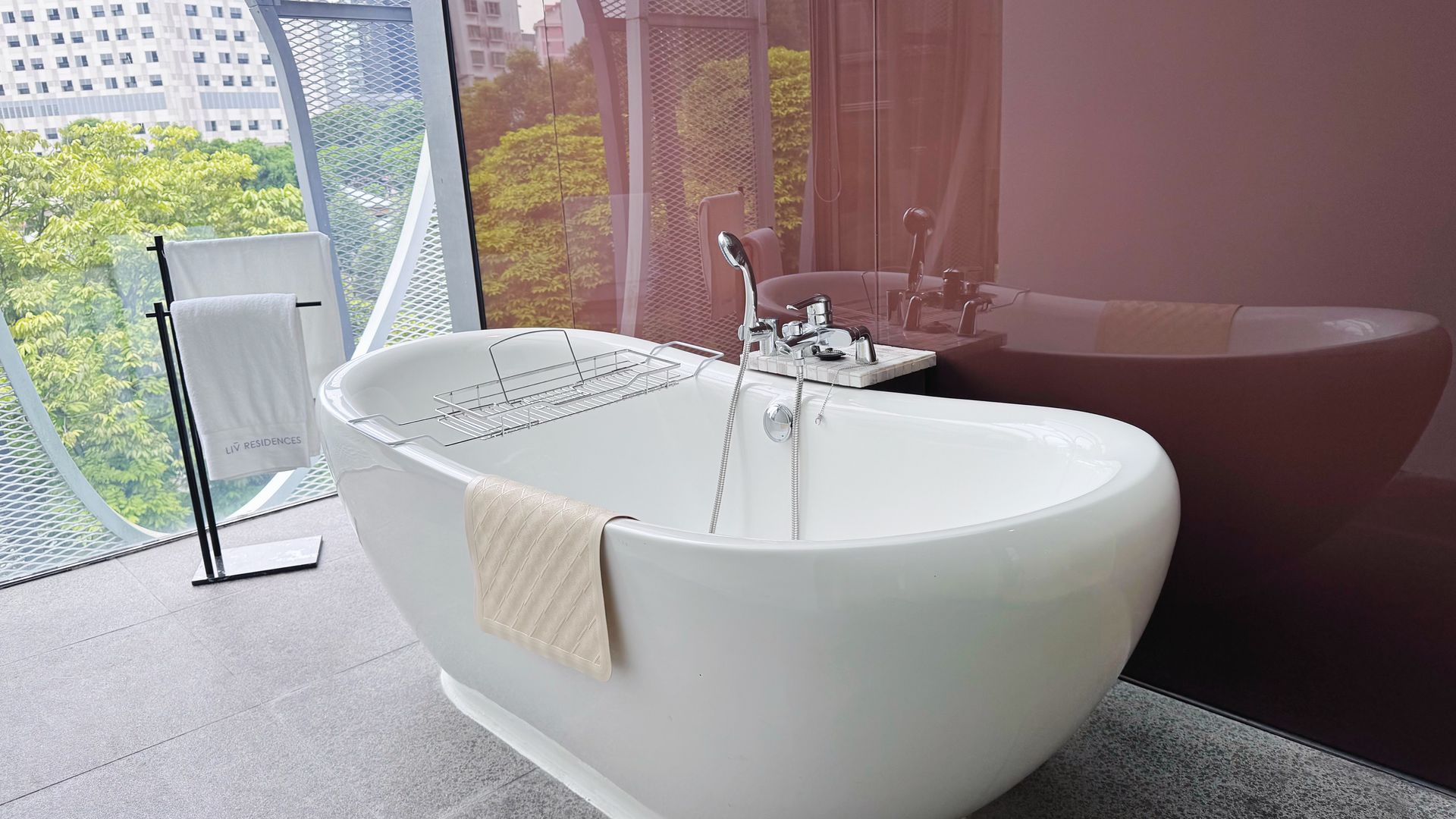 A modern bathroom with a white bathtub and a view of the outdoors.
