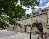 Stone building with hanging flower baskets and a curved road on a bright day.