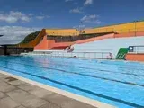 Outdoor swimming pool with blue water and colorful concrete buildings.