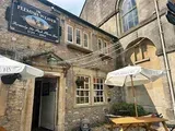 Exterior of the Fleming Arms pub, with umbrellas, tables, and a sign in Bath, England.