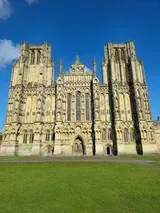 Wells Cathedral exterior against a bright blue sky.