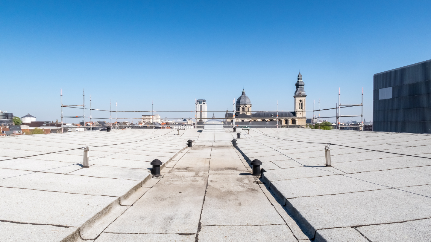 Rooftop view with a church and cityscape in the background under a blue sky.
