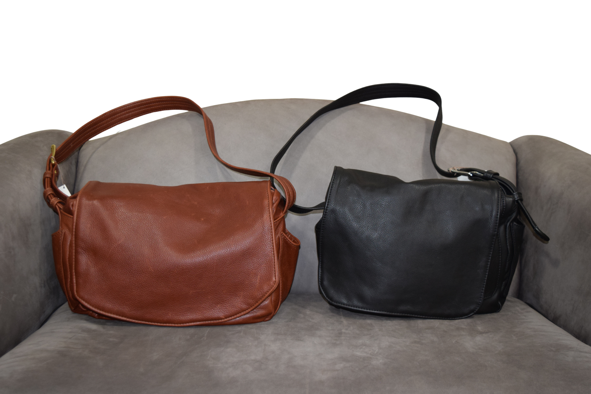 Brown and black leather messenger bags on a gray armchair.