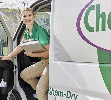 Chem-Dry employee in green shirt exits van with clipboard.
