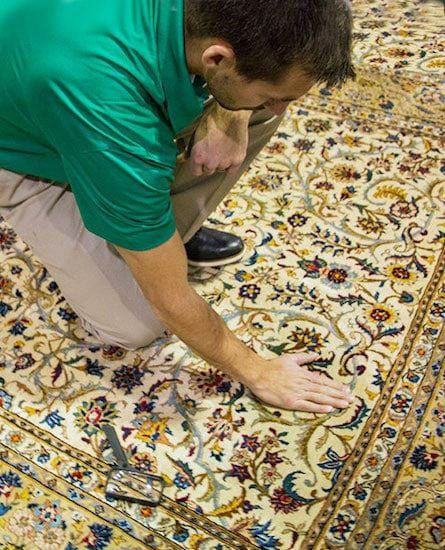 A Chem-Dry technician is inspecting an ornate rug.
