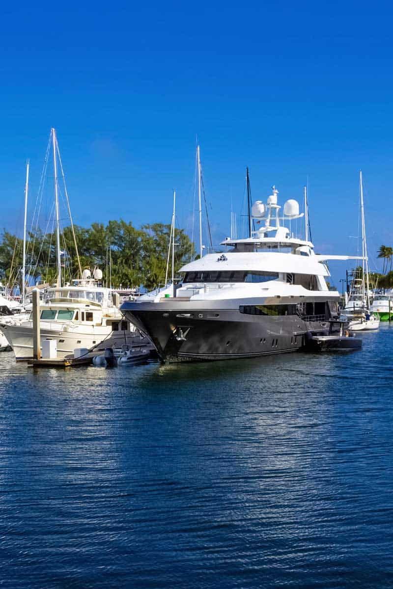 A large black and white yacht docked in a harbor with blue water and a clear sky.