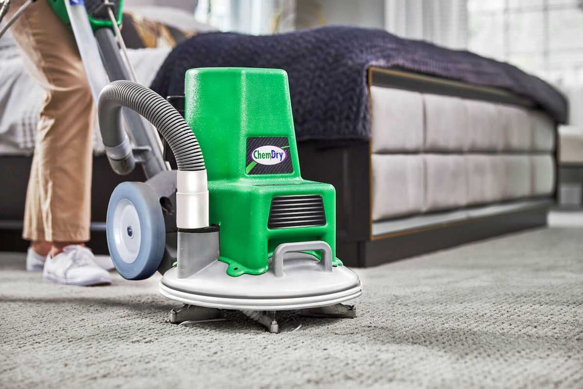 A Chem-Dry technician is cleaning a carpet with a Chem-Dry machine