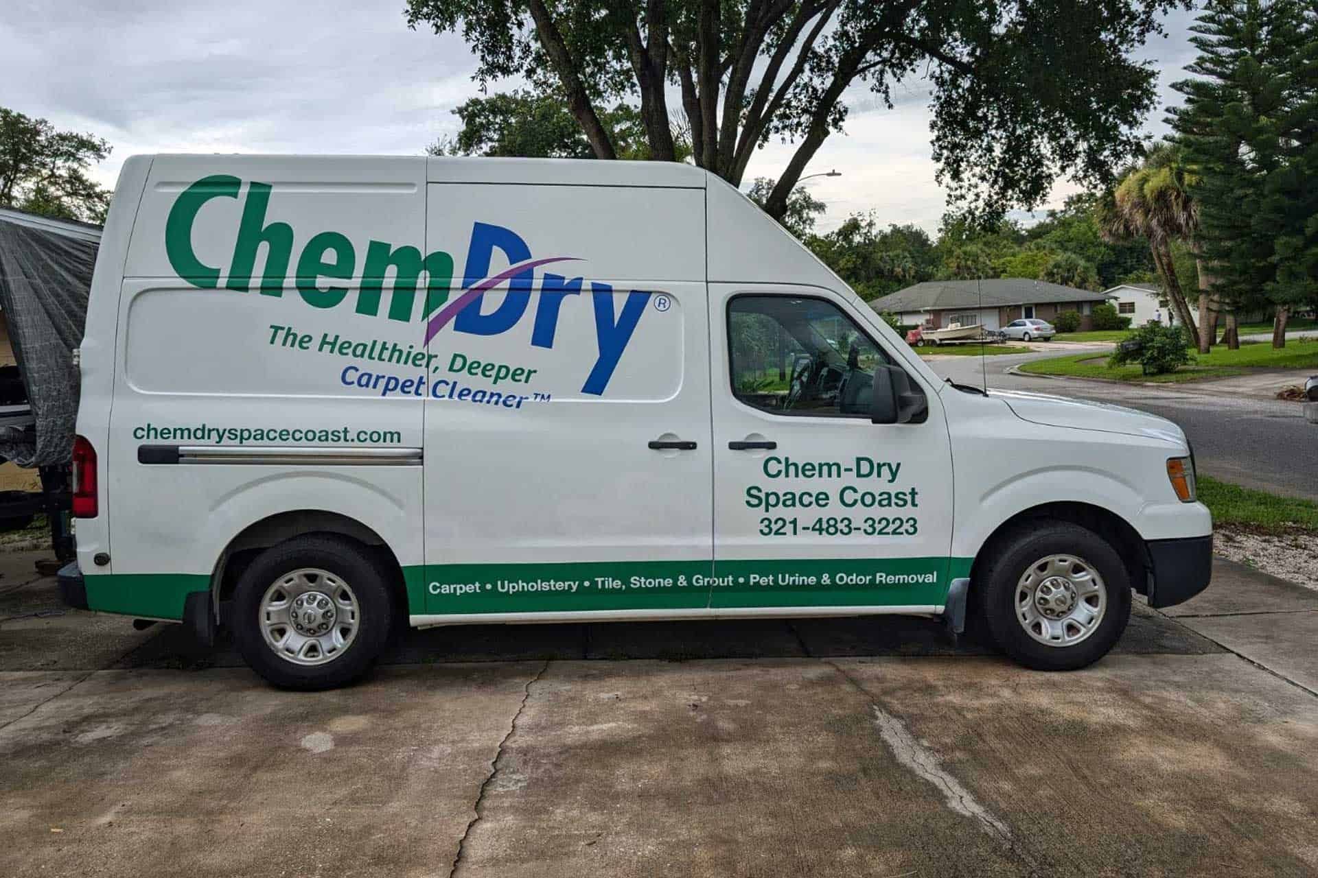 A chem dry space coast carpet cleaning van is parked in a parking lot.