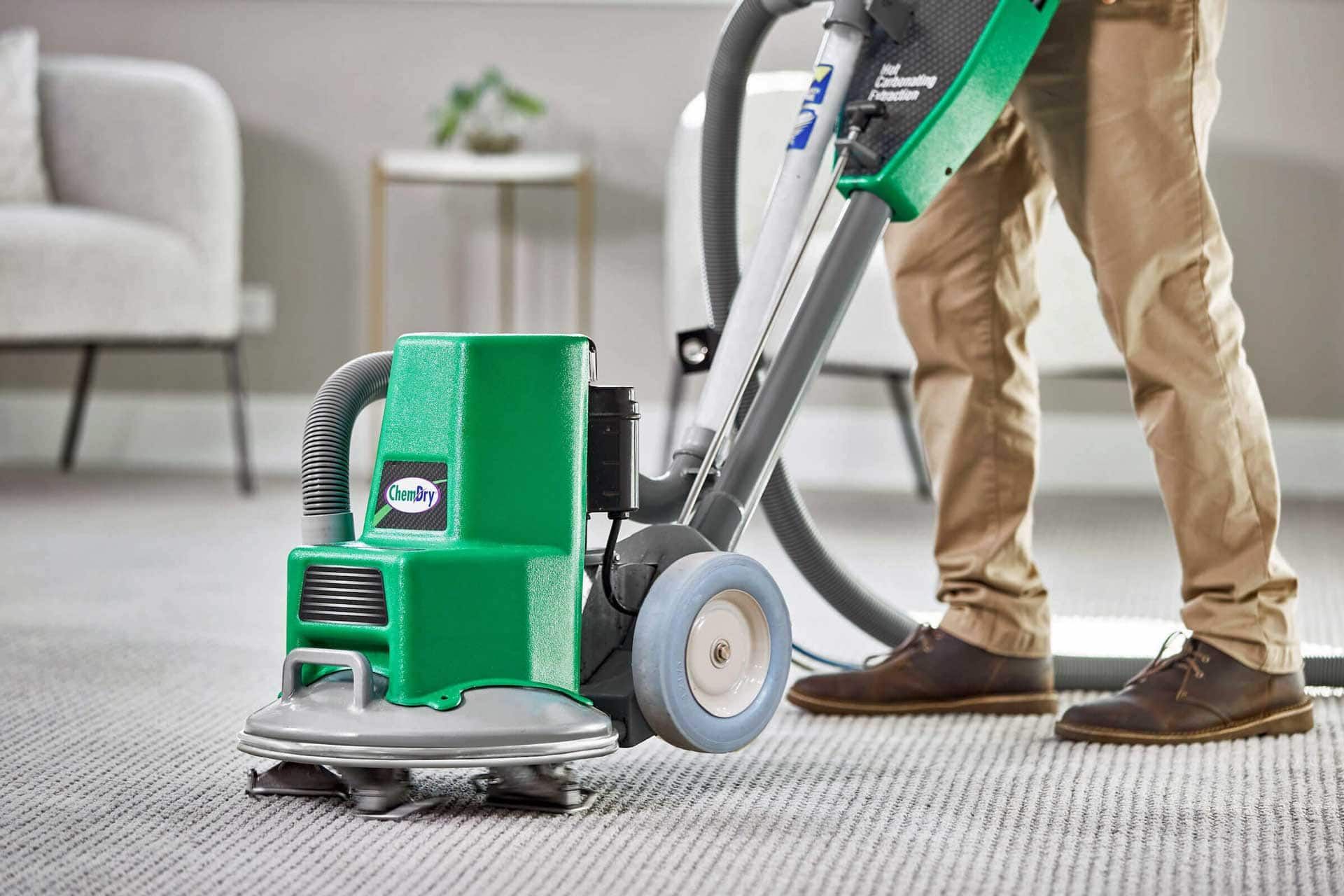 a man cleaning a carpet using a vacuum with the Hot Carbonating Extraction method
