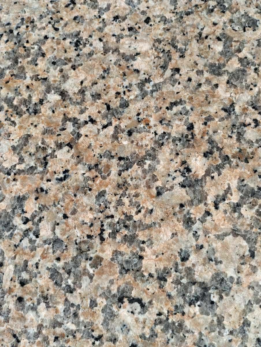 Close-up of speckled granite with beige, gray, and black mineral grains.