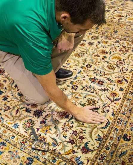 Chem-Dry tech in green shirt inspects floral rug.