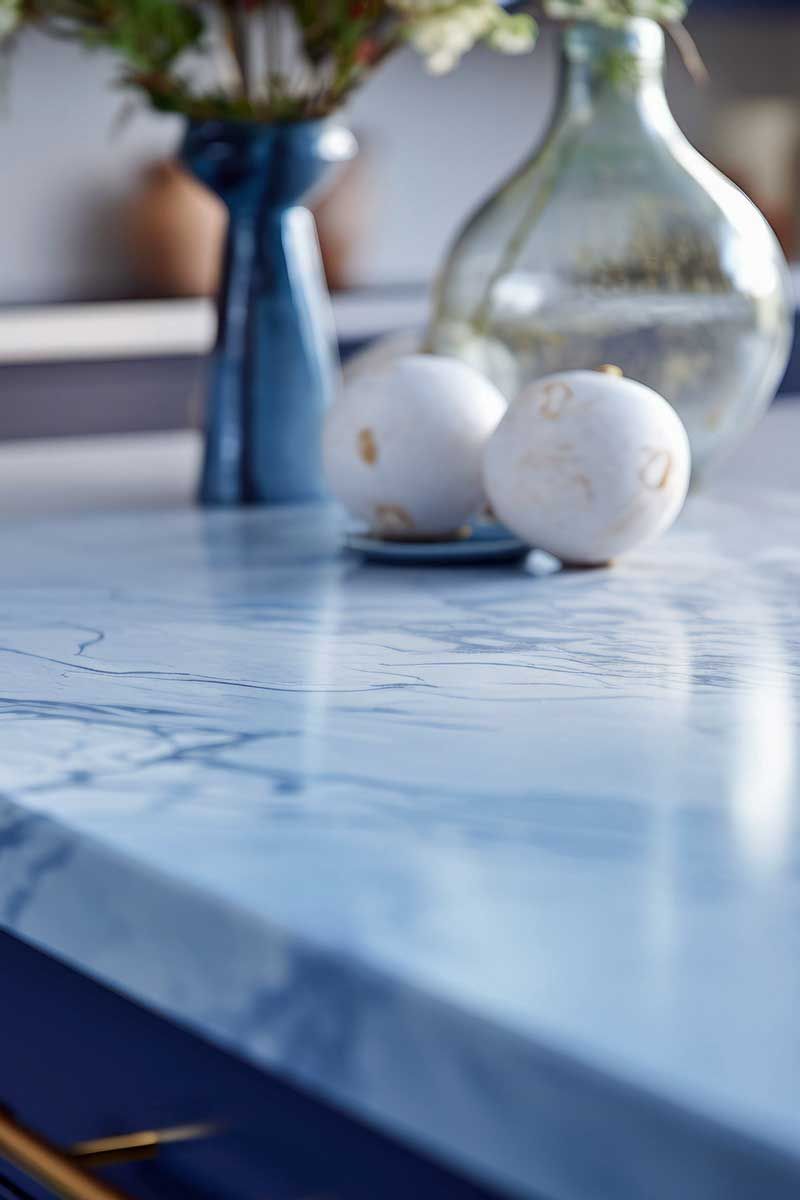 Close-up of marble a kitchen countertop with a marble pattern in blue tones, featuring white round vegetables and blue vases.