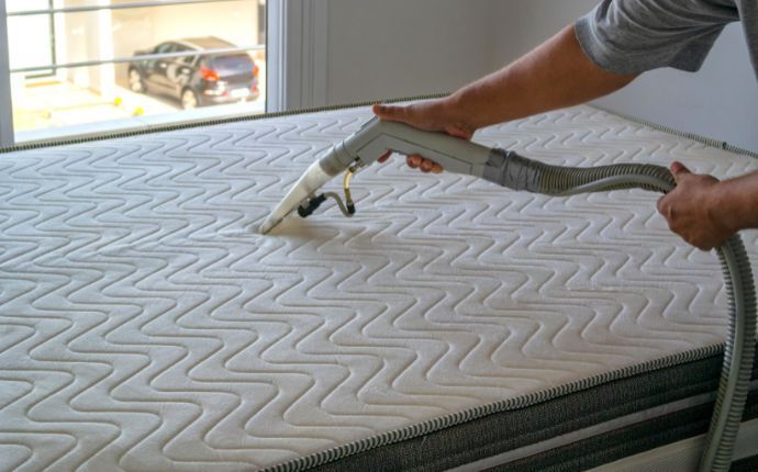 A Chem-Dry technician deep-cleans a mattress with a vacuum
