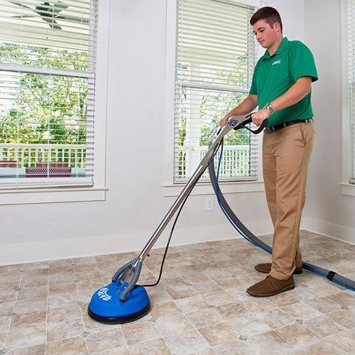 A Chem-Dry technician is cleaning a carpet with a chem-dry machine