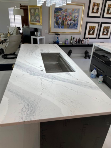 White marble countertop with a stainless steel sink, in a bright kitchen.