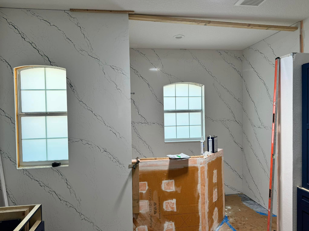 Kitchen renovation with white walls, black veining, two windows, and unfinished bar.