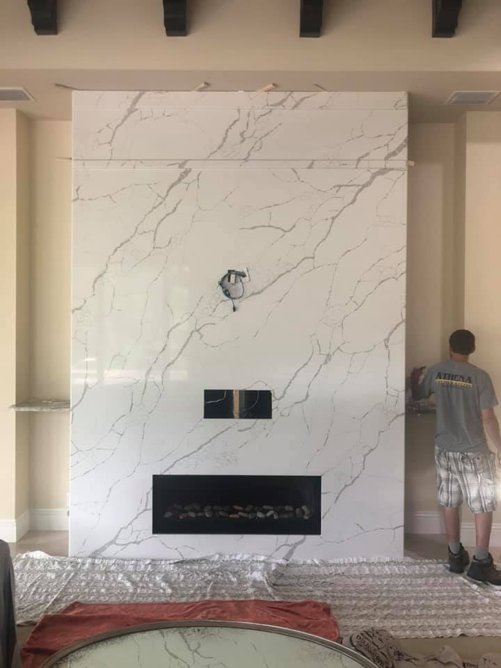 Fireplace with large white marble slab, worker at right.