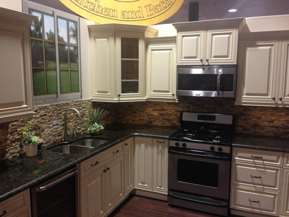 Cream-colored kitchen cabinets with a black countertop and stainless steel appliances.