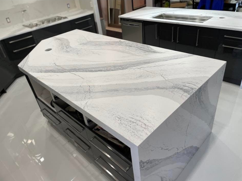 Modern kitchen island with gray and white marbled countertop, dark gray cabinets, and a stainless steel appliance.