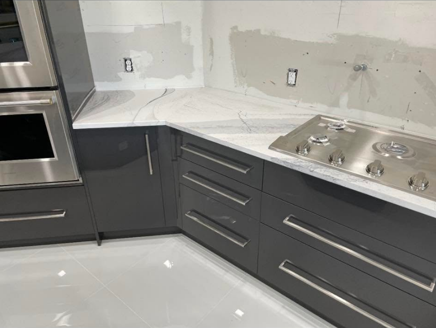 Kitchen corner with gray cabinets, white countertop, stainless steel stove and oven.