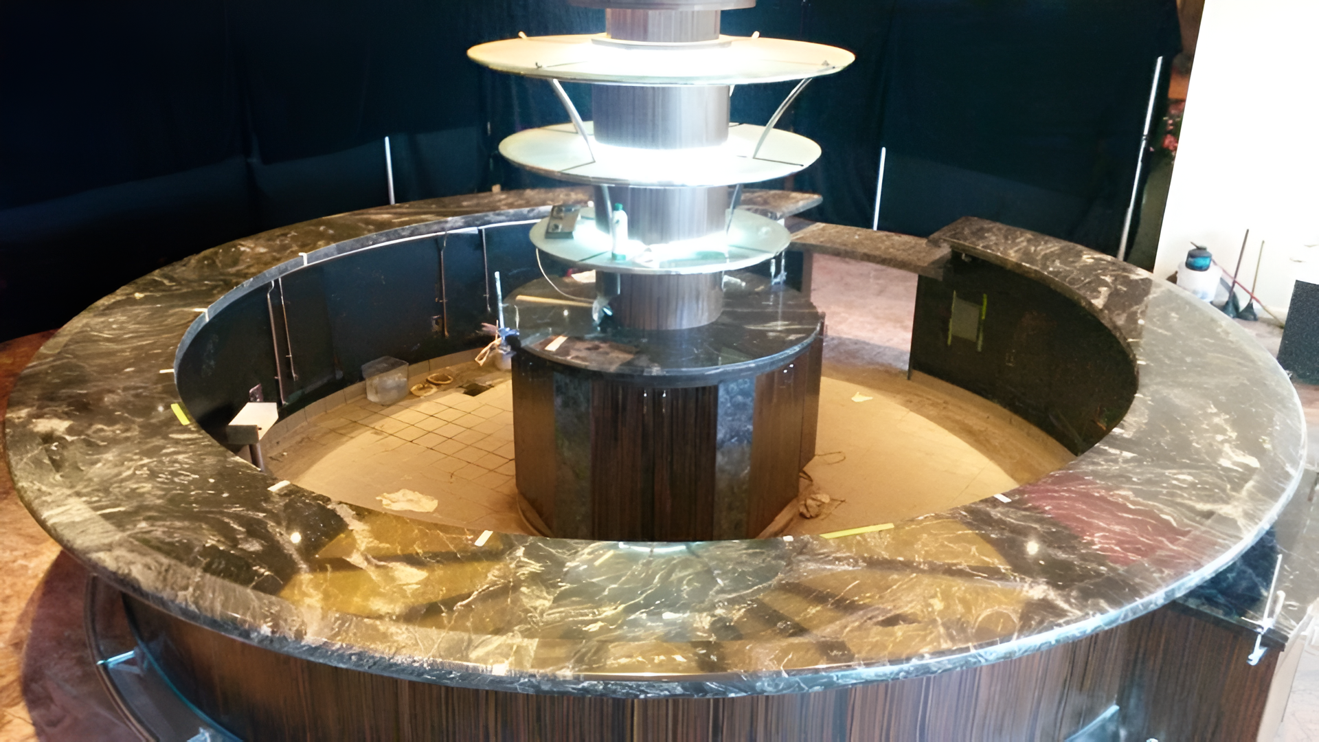 Chocolate fountain with a marble-topped serving station, brown wood base, dark chocolate cascading down.