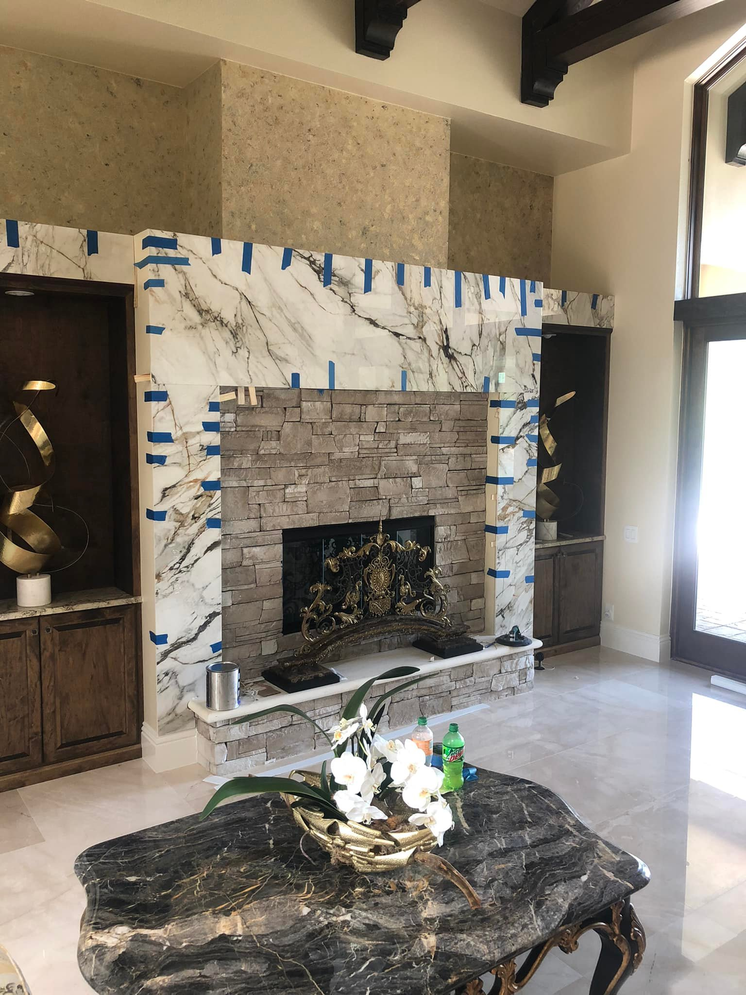 Living room with stone fireplace, marble, and built-in cabinets. A rustic coffee table sits in front.