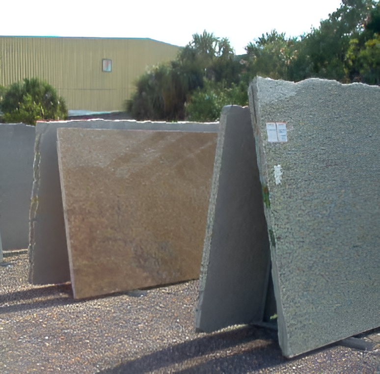 Stone slabs on display outdoors. Various colors, leaning against a rack, sunlight casting shadows.