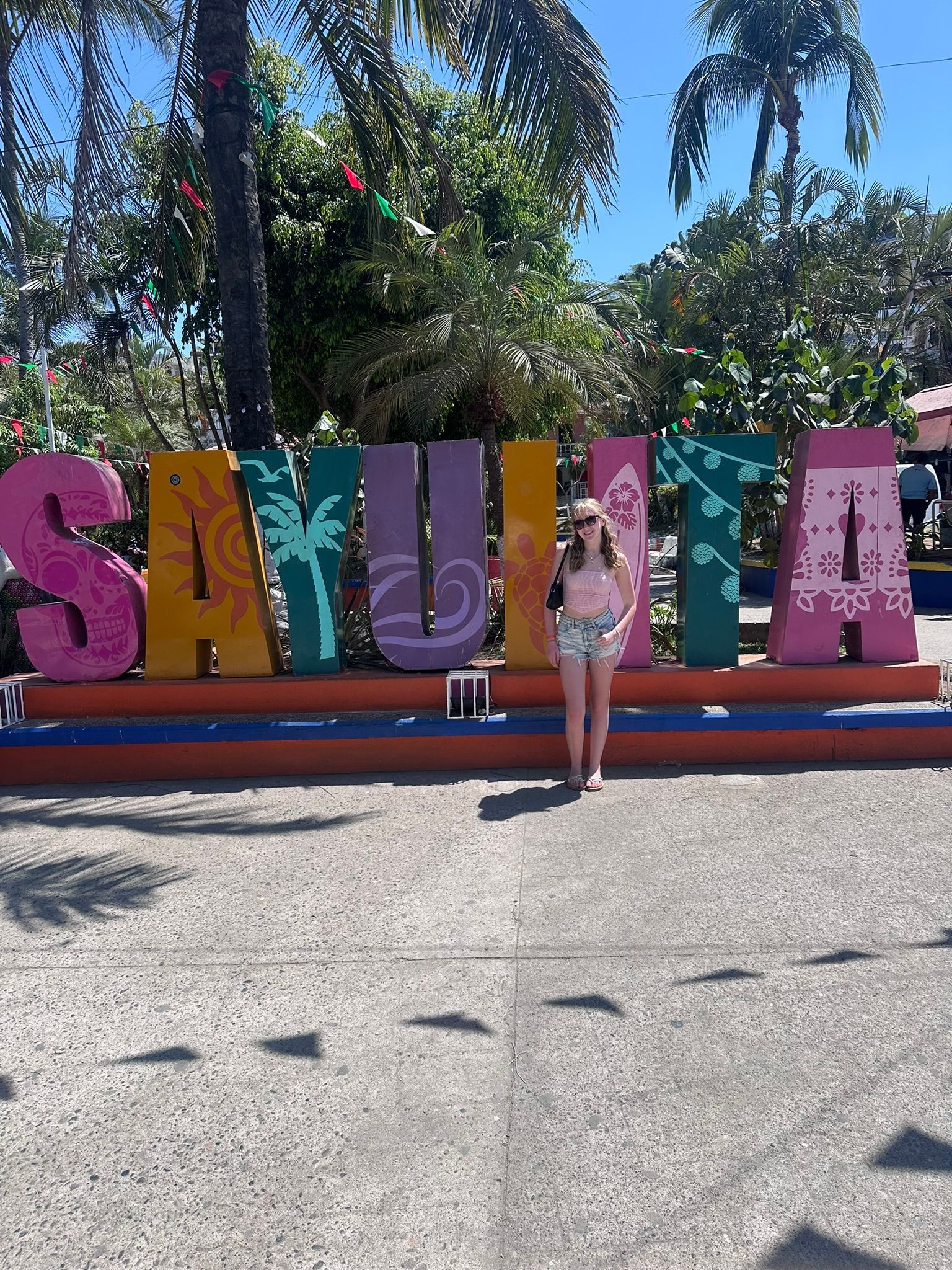 A woman is standing in front of a sign that says sayulita.
